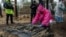 A forensic expert examines the body of a civilian during exhumation in the recently retaken area of Izium, Kharkiv region, Ukraine, Sept. 23, 2022.