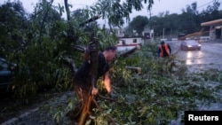 La gente despeja un camino de un árbol caído después de que el huracán Fiona afectó el área en Yauco, Puerto Rico el 18 de septiembre de 2022. REUTERS/Ricardo Arduengo