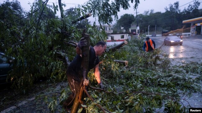 La gente despeja un camino de un árbol caído después de que el huracán Fiona afectó el área en Yauco, Puerto Rico el 18 de septiembre de 2022. REUTERS/Ricardo Arduengo