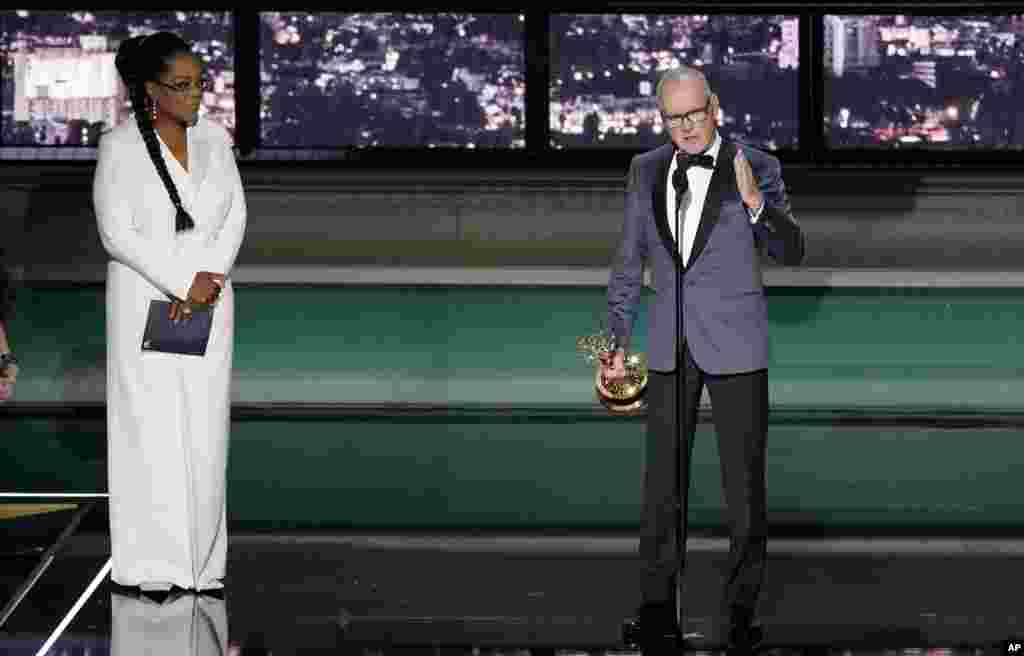 Michael Keaton, right, accepts the Emmy for outstanding lead actor in a limited or anthology series or movie for "Dopesick" at the 74th Primetime Emmy Awards at the Microsoft Theater in Los Angeles, Sept. 12, 2022. Oprah Winfrey looks on from stage left. 