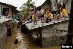 People wait on the roof of their homes for flooding to subside after Super Typhoon Noru, in San Miguel, Bulacan province, Philippines, Sept. 26, 2022. (REUTERS/Eloisa Lopez)
