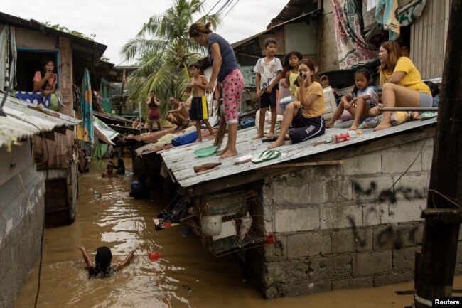 People wait on the roof of their homes for flooding to subside after Super Typhoon Noru, in San Miguel, Bulacan province, Philippines, Sept. 26, 2022. (REUTERS/Eloisa Lopez)