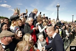 Britain's Prince William meets the public in the queue near to Lambeth Bridge as they wait to view Queen Elizabeth II lying in state, in London, Sept. 17, 2022.