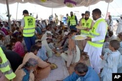 Relawan kelompok amal mendistribusikan makanan kepada korban banjir, di Jaffarabad, distrik yang dilanda banjir di provinsi Baluchistan, Pakistan, Kamis, 15 September 2022. (AP/Zahid Hussain)