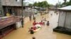 Residents give out free food as they wade through a flooded street in their village from Typhoon Noru in San Miguel town, Bulacan province, Philippines, Sept. 26, 2022. 