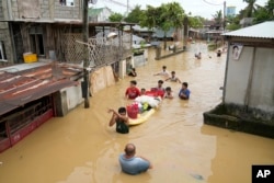 Warga membagikan makanan gratis saat mengarungi banjir di desa mereka akibat Topan Noru di Kota San Miguel, Provinsi Bulacan, Filipina, 26 September 2022. (Foto: AP)