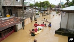 People wade through a flooded street in San Miguel town, Philippines, Sept. 26, 2022. Typhoon Noru went through northern Philippines on Monday, leaving several dead, causing floods and power outages. (AP Photo/Aaron Favila)