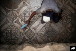 A Palestinian sweeps dust off parts of a Byzantine-era mosaic floor that was uncovered by a farmer in Bureij in central Gaza Strip, Sept. 5, 2022. . (AP Photo/Fatima Shbair)