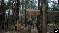 FILE - Oleg Kotenko, Commissioner for Issues of Missing Persons under Special Circumstances films the unidentified mass graves found near Izium, Ukraine, Sept. 15, 2022.