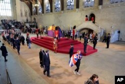 La gente presenta sus respetos mientras pasa junto al ataúd de la reina Isabel de Gran Bretaña, envuelta en el estandarte real con la corona del estado imperial y el orbe y el cetro del soberano, dentro del Westminster Hall en Londres, el 16 de septiembre de 2022.