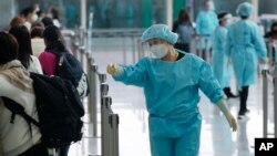 身穿防护服的香港机场工作人员指引抵港旅客排队前往防疫隔离酒店。（2022年4月1日）
