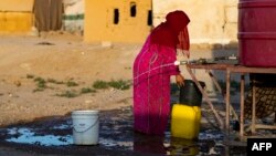 A Syrian woman fills a container with water at the Sahlah al-Banat camp in the countryside of Raqa, in northern Syria, on Sept. 19, 2022. The World Health Organization warned on Sept. 14 of a "very high" risk of cholera spreading throughout Syria. 