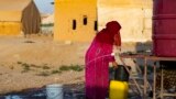  شام میں ہیضے کی وبا کے دوران رقہ شام کے ایک کیمپ میں ایک شامی عورت ایک کنٹینر میں پانی بھر رہی ہے ۔ فوٹو اے ایف پی ۔19 ستمبر 2022 