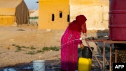  شام میں ہیضے کی وبا کے دوران رقہ شام کے ایک کیمپ میں ایک شامی عورت ایک کنٹینر میں پانی بھر رہی ہے ۔ فوٹو اے ایف پی ۔19 ستمبر 2022 