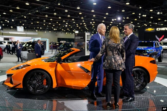 President Joe Biden talks with Mary Barra, CEO of General Motors, center, and an unidentified man, during a tour of the Detroit Auto Show, Sept. 14, 2022, in Detroit.