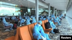 Warga negara Vietnam yang mengenakan APD menunggu di bandara untuk menaiki penerbangan repatriasi dari Singapura ke Vietnam di tengah penyebaran wabah COVID-19 di Bandara Changi, Singapura 7 Agustus 2020. (Foto: REUTERS/Mai Nguyen)