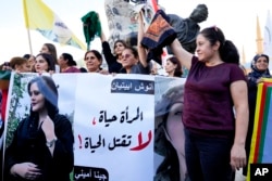 FILE - Kurdish women activists hold headscarfs and a portrait of Iranian woman Mahsa Amini, with Arabic that reads, "The woman is life, don't kill the life," during a protest against her death in Iran, at Martyrs' Square in downtown Beirut, Sept. 21, 2022