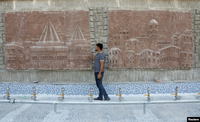 The sculptor Khaled al-Abadi looks at sculptures he completed which depict scenes from the history of the city of Mosul, in Mosul, Iraq, September 15, 2022. (REUTERS/Khalid al-Mousily)