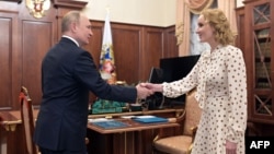 FILE - Russian President Vladimir Putin meets with Commissioner for Children's Rights Maria Lvova-Belova at the Kremlin in Moscow, March 9, 2022. The commissioner, who is being sought for war crimes for deporting children from Ukraine, said Wednesday they were taken for safety. 