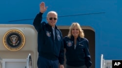 U.S. President Joe Biden waves as first lady Jill Biden watches standing at the top of the steps of Air Force One before boarding at Andrews Air Force Base, Md., Sept. 17, 2022. 