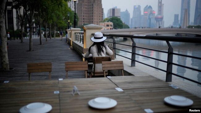 A woman sits in a restaurant on a river bank, following the coronavirus disease (COVID-19) outbreak, in Shanghai, China, September 6, 2022. (REUTERS/Aly Song)