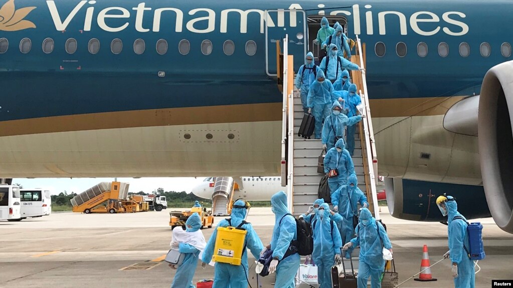 Nhân viên y tế phun khử khuẩn khi những hành khách là công dân Việt Nam xuống sân bay sau chuyến bay hồi hương từ Singapore giữa đại dịch COVID, tại Sân bay Cần Thơ ngày 7/8/2020. Bộ Công an vừa đề nghị truy tố hàng chục quan chức nhận hối lộ trong vụ chuyến bay "giải cứu".