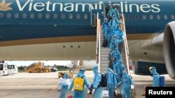 Nhân viên y tế xịt khuẩn những công dân Việt Nam hồi hương sau khi đáp chuyến bay do Bộ Ngoại giao tổ chức từ Singapore xuống sân bay Cần Thơ trong thời gian đại dịch COVID-19 hôm 7/8/2020.