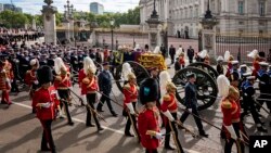 The coffin of Queen Elizabeth II with the Imperial State Crown resting on top, borne on the State Gun Carriage of the Royal Navy proceeds past Buckingham Palace in London, during the state funeral of Queen Elizabeth II, Monday Sept. 19, 2022. (Jenny Gooda