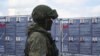 FILE - A Russian service member stands next to a mobile recruitment center for military service under contract in Rostov-on-Don, Russia, Sept. 17, 2022. 