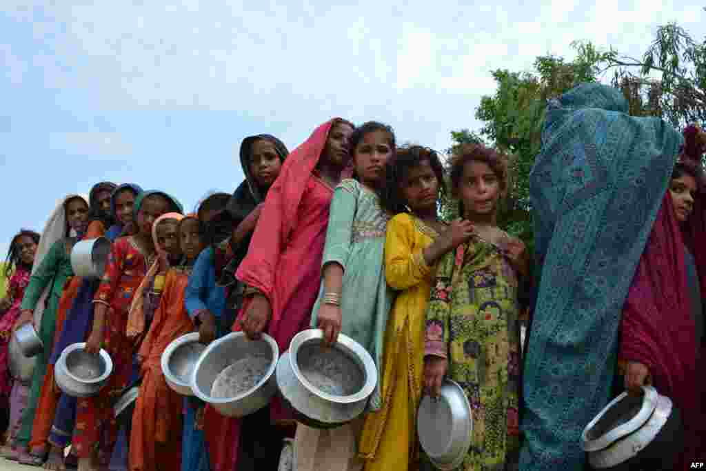 Displaced flood-affected people stand in a queue to receive food being distributed by Saylani Welfare Trust at a makeshift camp in the flood-hit city of Sehwan in Sindh province, Pakistan.