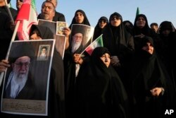 Iranian pro-government demonstrators hold posters of the Supreme Leader Ayatollah Ali Khamenei during their rally condemning recent anti-government protests over the death of Mahsa Amini, a 22-year-old woman who had been detained by the nation's morality police, in Tehran, Iran, Sunday, Sept. 25, 2022.