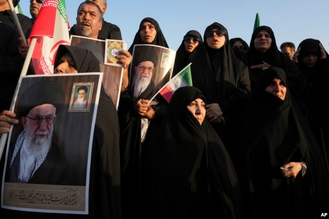 Iranian pro-government demonstrators hold posters of the Supreme Leader Ayatollah Ali Khamenei during their rally condemning recent anti-government protests over the death of Mahsa Amini, a 22-year-old woman who had been detained by the nation's morality police, in Tehran, Iran, Sunday, Sept. 25, 2022.