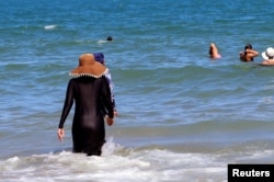 A woman, wearing a full-body burkini swimsuit, enjoys the sea at a beach in La Marsa, near Tunis, Tunisia September 11, 2022. (REUTERS/Jihed Abidellaoui)