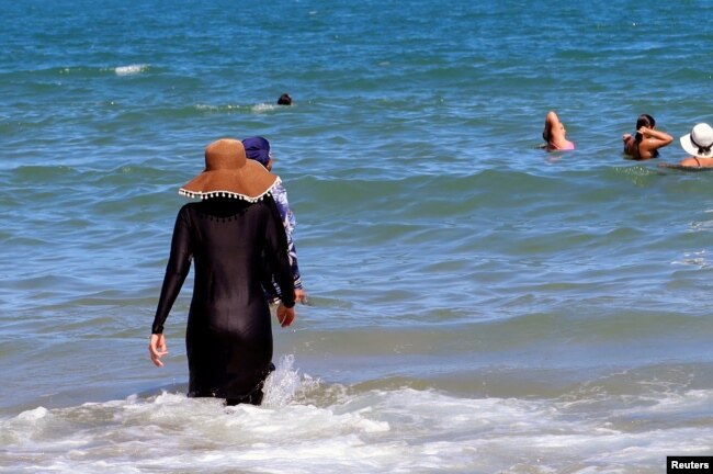 A woman, wearing a full-body burkini swimsuit, enjoys the sea at a beach in La Marsa, near Tunis, Tunisia September 11, 2022. (REUTERS/Jihed Abidellaoui)