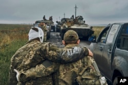 A Ukrainian soldier helps a wounded comrade on the road in liberated territory in the Kharkiv region on September 12, 2022. (Kostiantyn Liberov/AP)