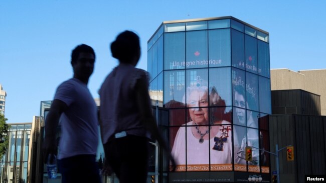 People walk by as a tribute to Queen Elizabeth appears on the National Arts Centre, after Queen Elizabeth's passing, in Ottawa, Ontario, Canada, September 8, 2022. REUTERS/Patrick Doyle