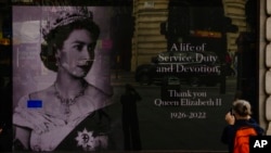 FILE: A tourist takes a photo of a display commemorating Queen Elizabeth II, at Piccadilly Circus in London, Sept. 11, 2022. 