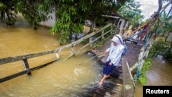 Seorang siswa berjalan melewati jembatan kayu yang rusak akibat luapan air sungai menyusul banjir yang terjadi di Desa Jaranih, Sungai Hulu Tengah, Kalimantan Selatan, pada 17 November 2021. (Foto: Antara via Reuters/Bayu Pratama)