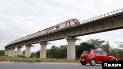 FILE - A car passes under a bridge as a train moves along the Standard Gauge Railway line n Athi River, Kenya, June 3, 2022.