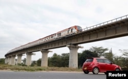 FILE - A car passes under a bridge as a train moves along the Standard Gauge Railway (SGR) line n Athi River, Kenya, June 3, 2022.