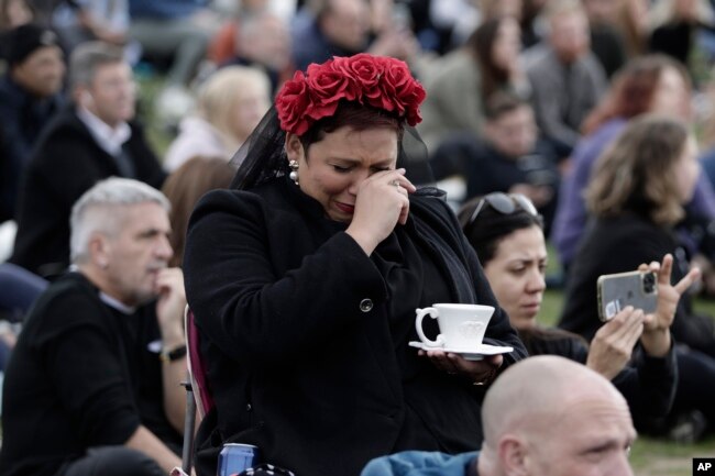 A woman reacts in Hyde Park while watching the State Funeral Service of Britain's Queen Elizabeth II on giant screens, Monday, Sept. 19, 2022 in London. (AP Photo/Lewis Joly)