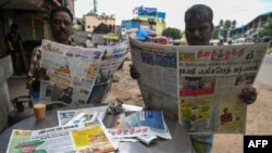 Varias personas leen periódicos con noticias del fallecimiento de la reina Isabel II, en Chennai, el 9 de septiembre de 2022. (Foto de Arun SANKAR / AFP)