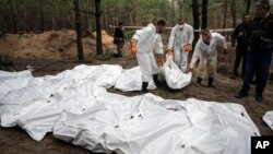 Experts work during the exhumation of bodies in the recently retaken area of Izium, Ukraine, Sept. 16, 2022.