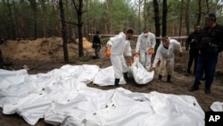 Experts work during the exhumation of bodies in the recently retaken area of Izium, Ukraine, Sept. 16, 2022.