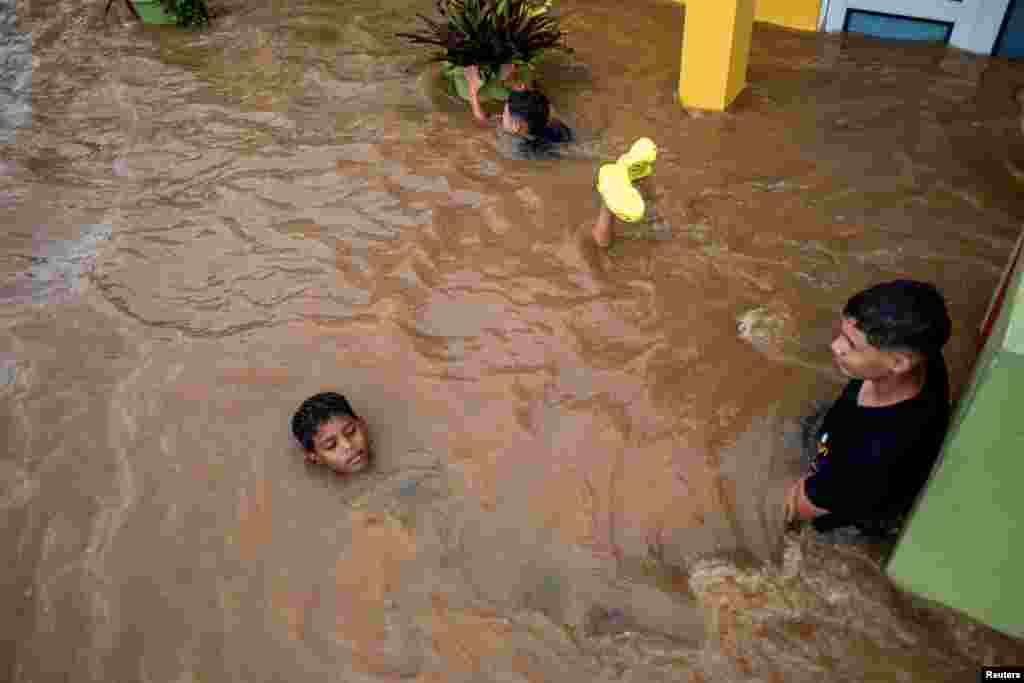 Children play in a flooded street in the aftermath of Hurricane Fiona in Salinas, Puerto Rico, Sept. 19, 2022. 