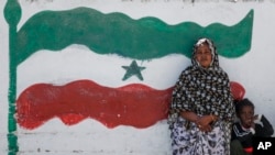 FILE - A woman and child relax next to a mural of Somaliland's flag, in Hargeisa, Somaliland, a semi-autonomous breakaway region in Somalia, Feb. 9, 2022.