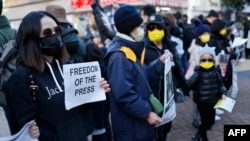 Protesters hold placards in south west London on January 9, 2022 to demonstrate against the 'dramatic deterioration of press freedom' in Hong Kong.