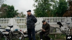 An elderly man looks at a book as he sits on a bench in the recaptured area of Izium, Ukraine, Sept. 14, 2022