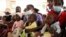 Women holding babies take their places on wooden benches at a clinic in Harare, Zimbabwe, Thursday, Sept. 15, 2022. 