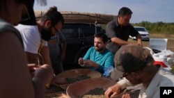 From left, Kendra Haugen, David Villier, Joey Riley, Ryan White and Nate Johnson hand-clean wild rice before cooking it over a fire, Sept. 12, 2022, at the Leech Lake Tribal College in Cass Lake, Minnesota.